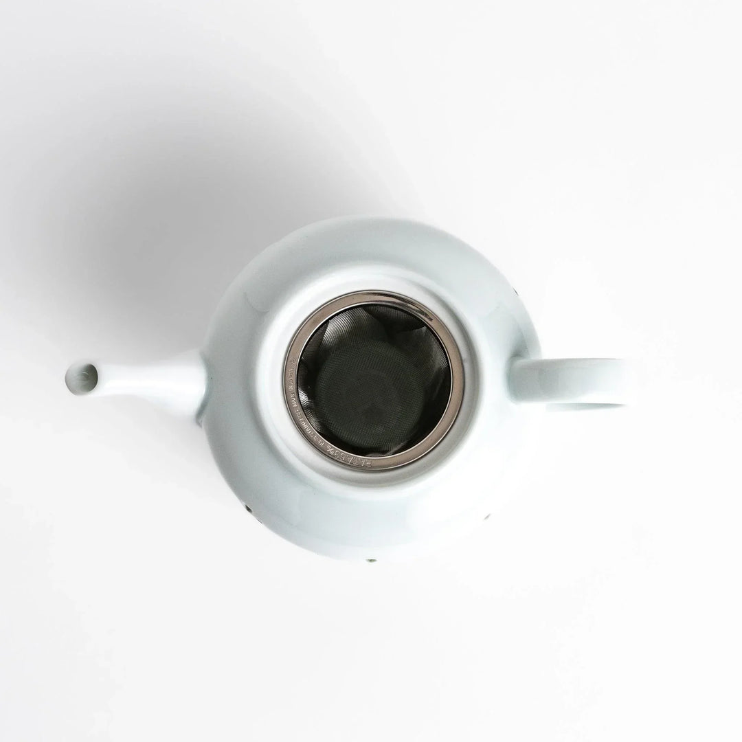 Elegant Japanese porcelain teapot with petal cutouts pointed lid and smooth handle for refined tea time.