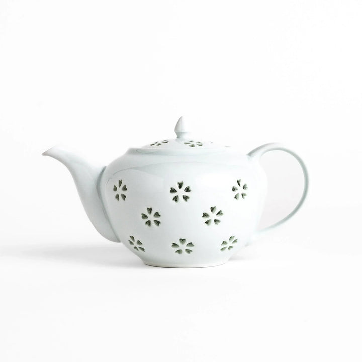 Elegant Japanese porcelain teapot with petal cutouts pointed lid and smooth handle for refined tea time.