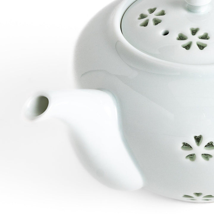 Elegant Japanese porcelain teapot with petal cutouts pointed lid and smooth handle for refined tea time.