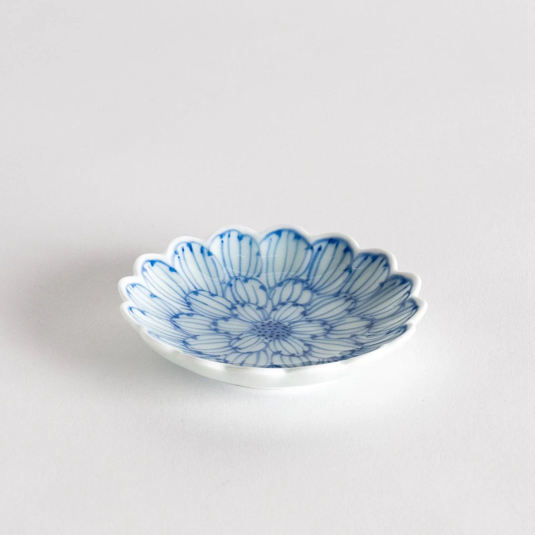 A small round dessert bowl with a delicate blue chrysanthemum pattern and scalloped edges.
