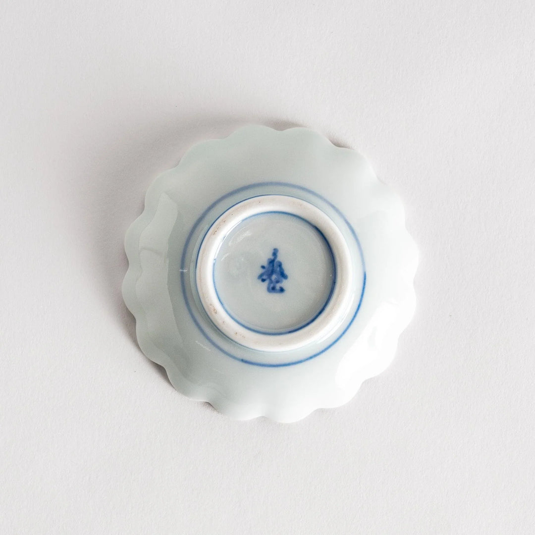 A small round dessert bowl with a delicate blue chrysanthemum pattern and scalloped edges.