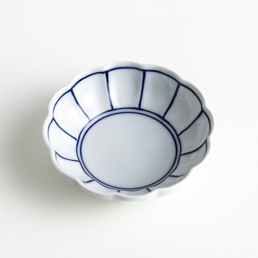 Small white porcelain condiment bowl with blue or red radiating lines for simple elegant table design.