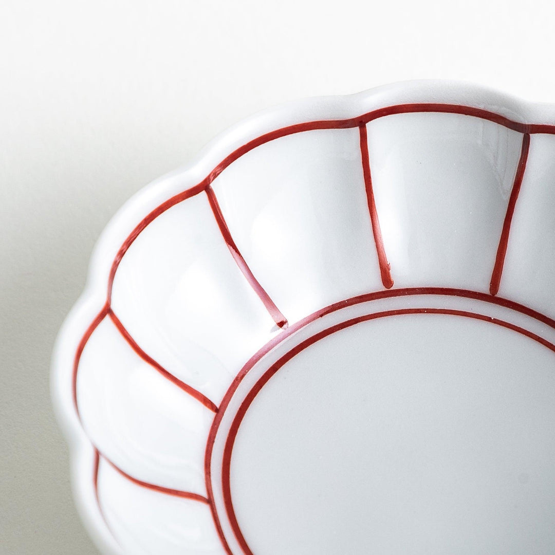Small white porcelain condiment bowl with blue or red radiating lines for simple elegant table design.