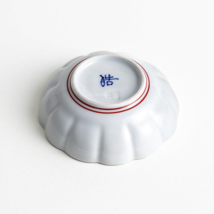 Small white porcelain condiment bowl with blue or red radiating lines for simple elegant table design.