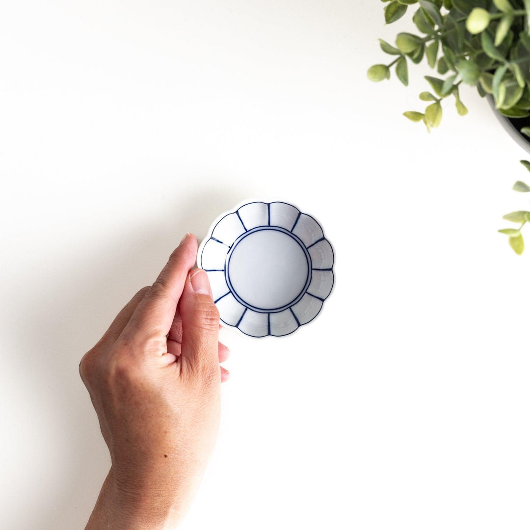 Small white porcelain condiment bowl with blue or red radiating lines for simple elegant table design.