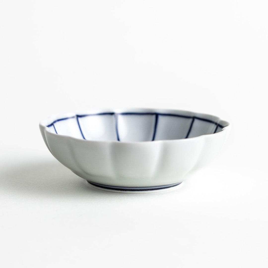 Small white porcelain condiment bowl with blue or red radiating lines for simple elegant table design.