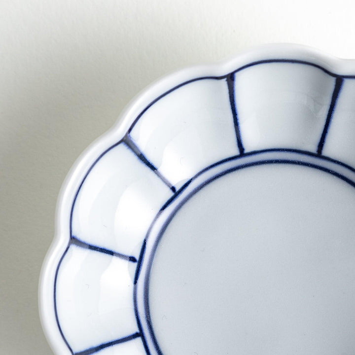 Small white porcelain condiment bowl with blue or red radiating lines for simple elegant table design.