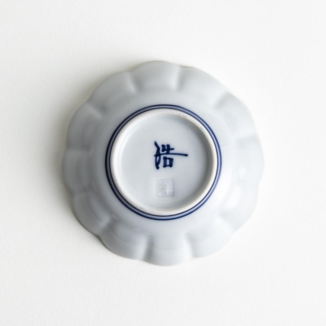 Small white porcelain condiment bowl with blue or red radiating lines for simple elegant table design.