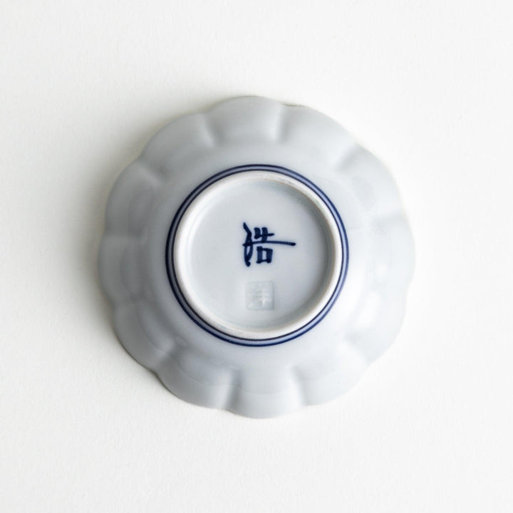 Small white porcelain condiment bowl with blue or red radiating lines for simple elegant table design.