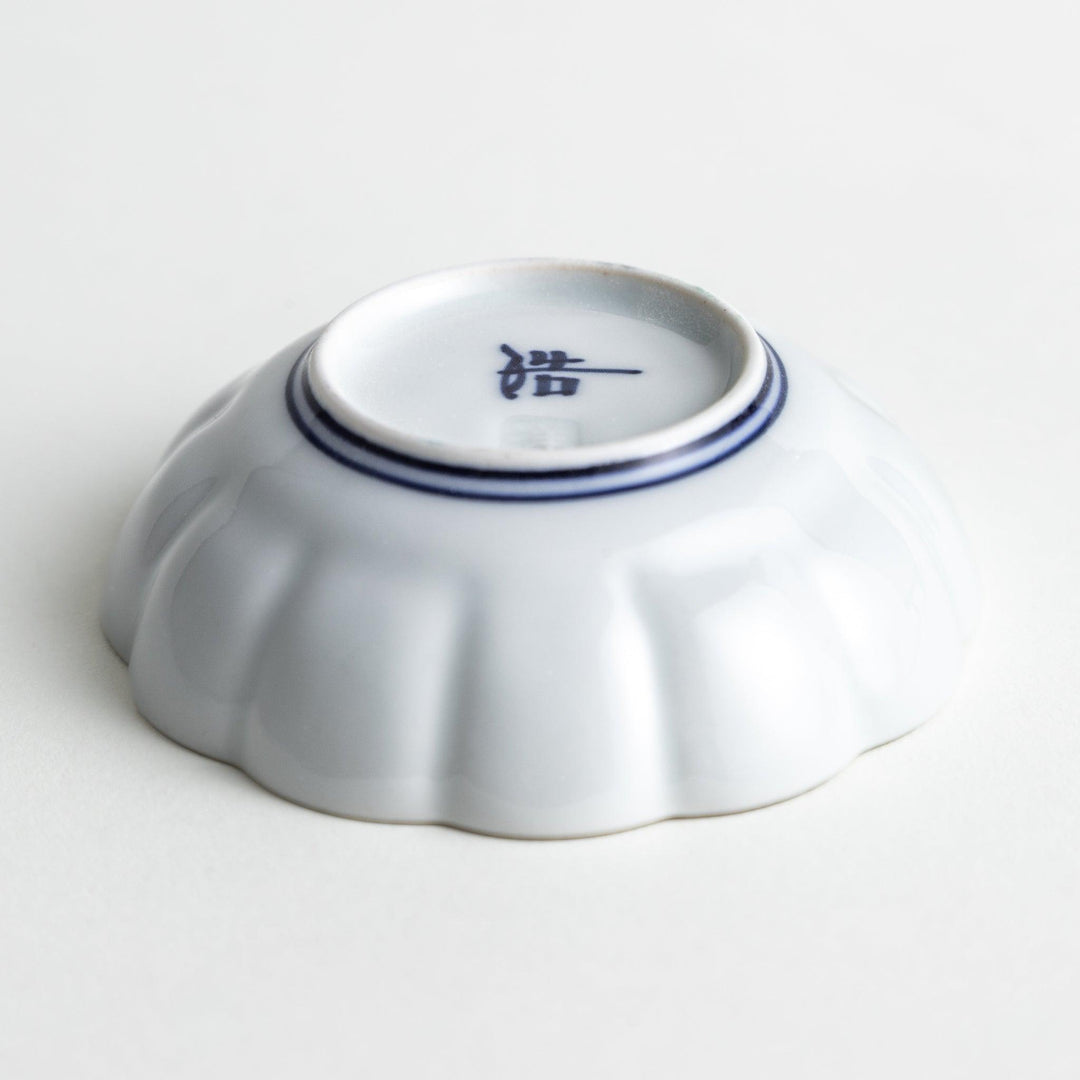 Small white porcelain condiment bowl with blue or red radiating lines for simple elegant table design.