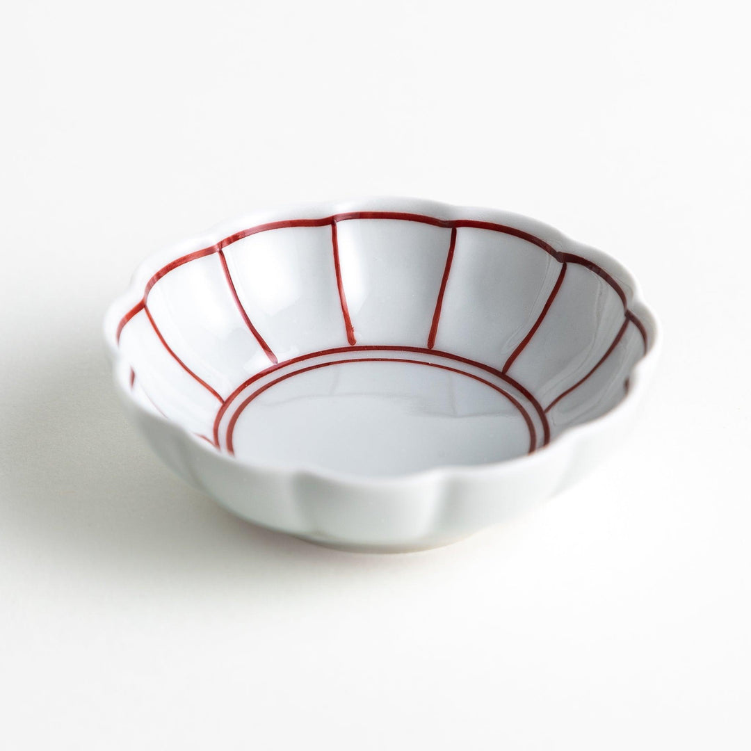 Small white porcelain condiment bowl with blue or red radiating lines for simple elegant table design.