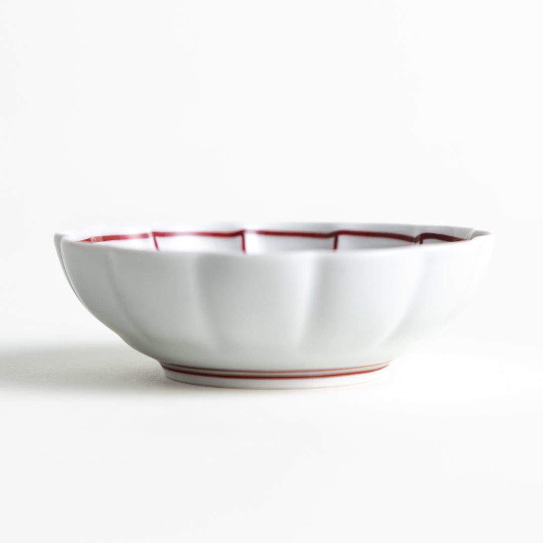 Small white porcelain condiment bowl with blue or red radiating lines for simple elegant table design.
