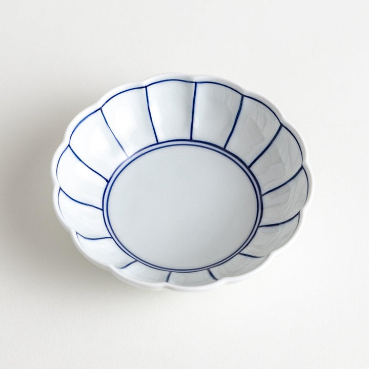 Small white porcelain dessert bowl with blue or red radiating lines for refined minimalist presentation.
