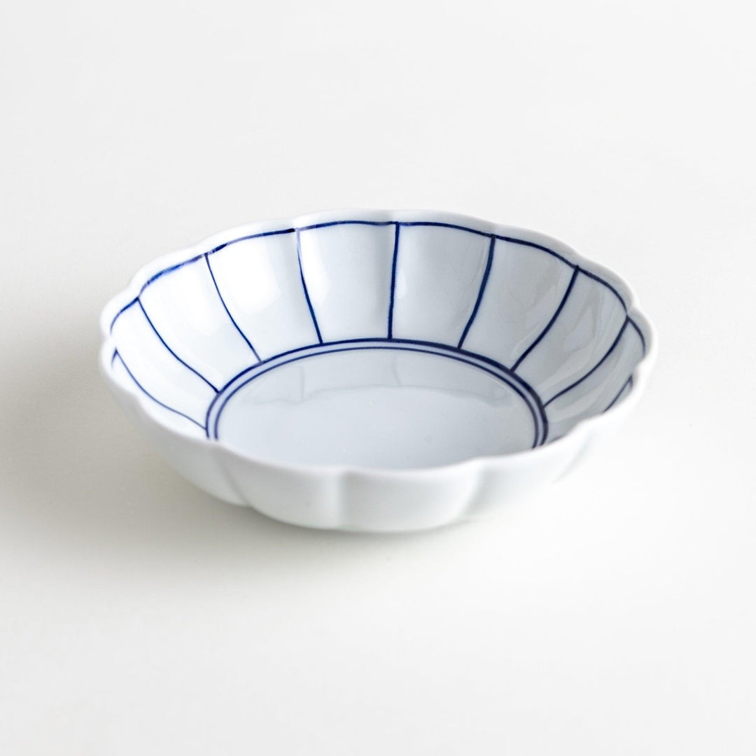Small white porcelain dessert bowl with blue or red radiating lines for refined minimalist presentation.