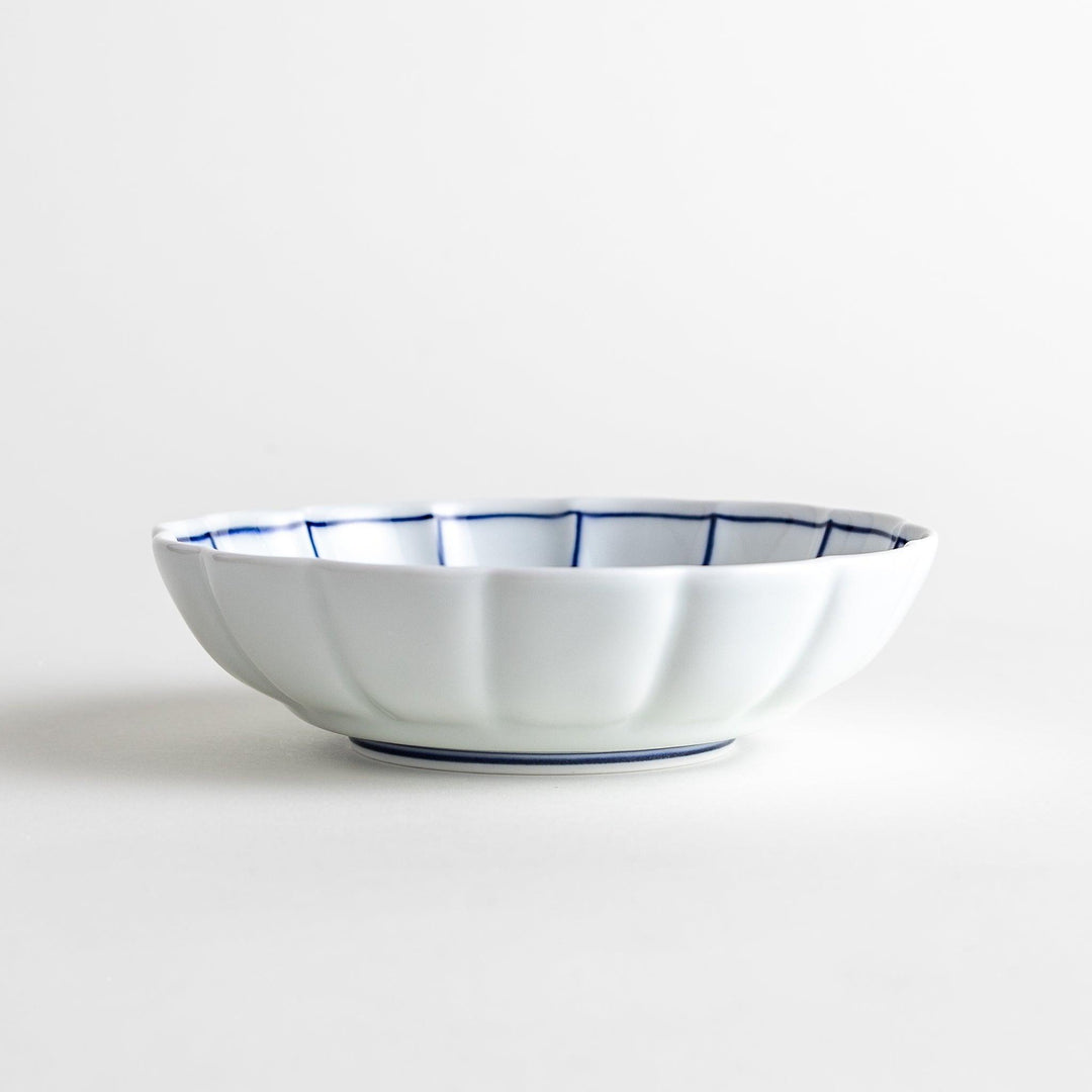 Small white porcelain dessert bowl with blue or red radiating lines for refined minimalist presentation.