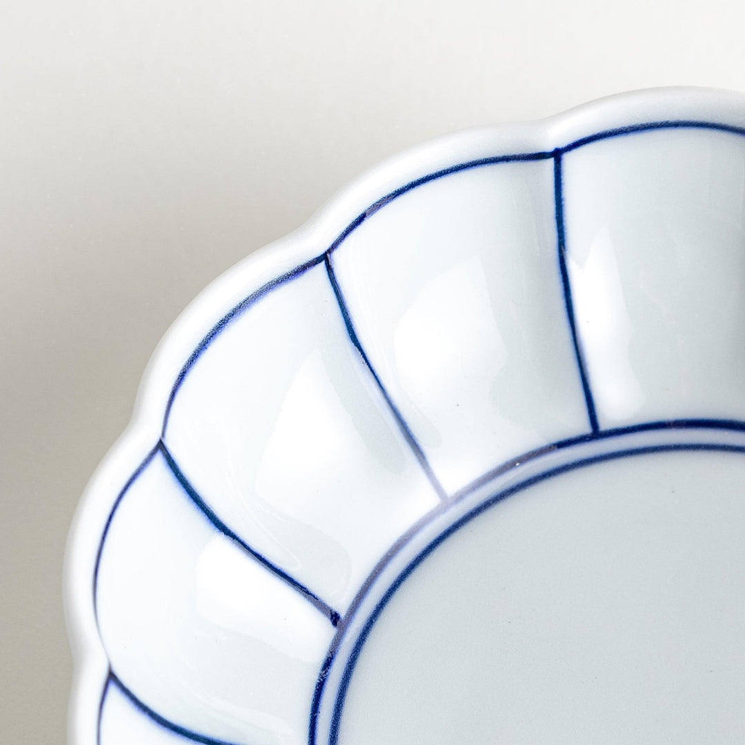 Small white porcelain dessert bowl with blue or red radiating lines for refined minimalist presentation.
