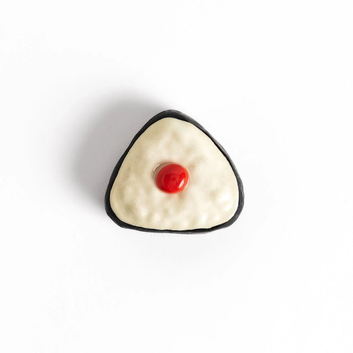 Pickled plum onigiri chopstick rest with red plum and black seaweed detail adding playful Japanese touch.