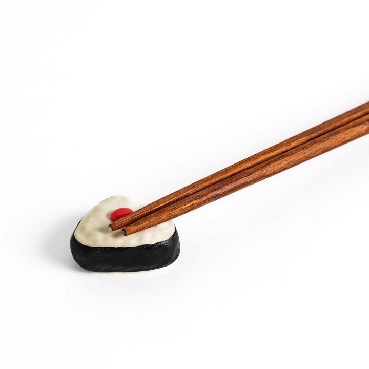 Pickled plum onigiri chopstick rest with red plum and black seaweed detail adding playful Japanese touch.