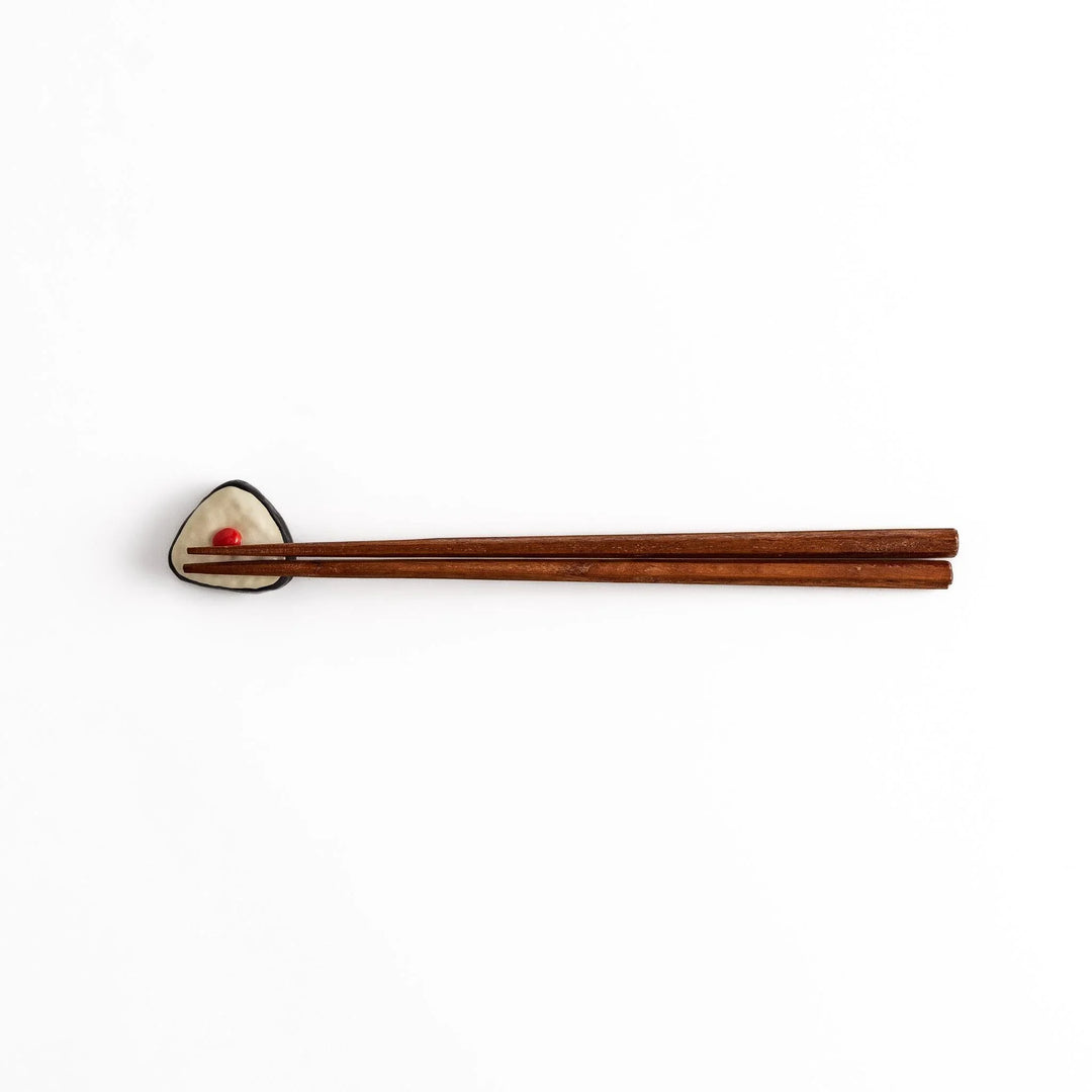 Pickled plum onigiri chopstick rest with red plum and black seaweed detail adding playful Japanese touch.