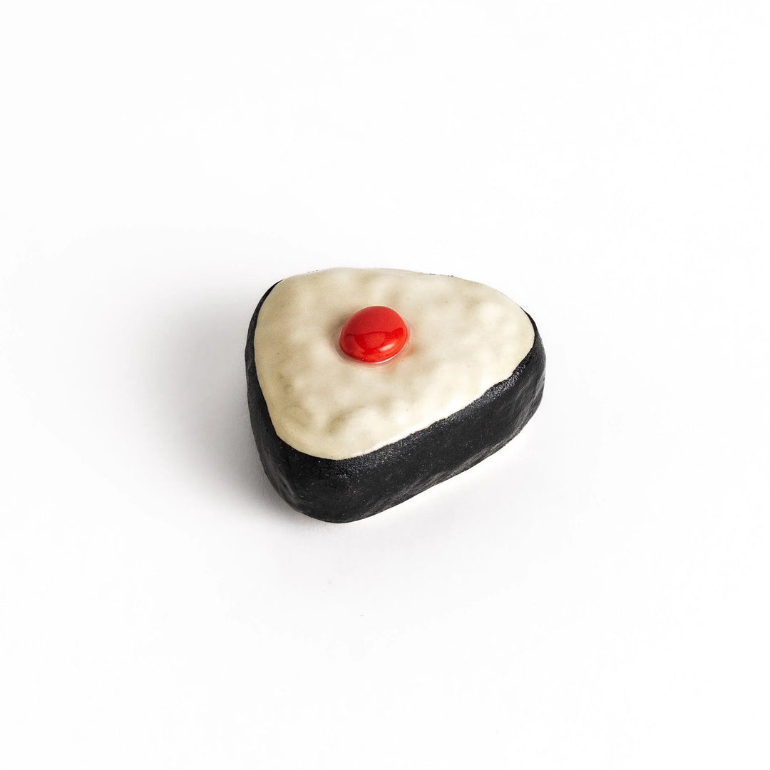 Pickled plum onigiri chopstick rest with red plum and black seaweed detail adding playful Japanese touch.