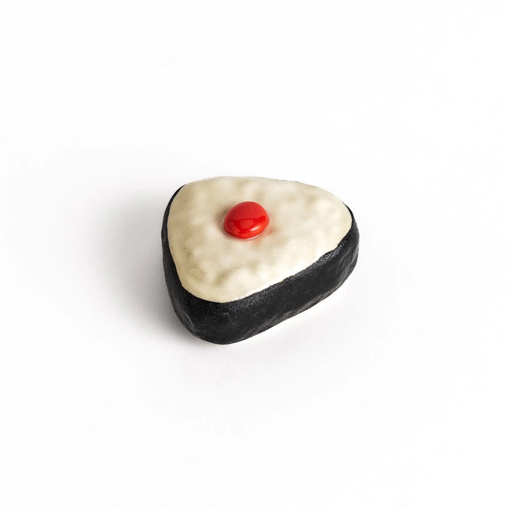 Pickled plum onigiri chopstick rest with red plum and black seaweed detail adding playful Japanese touch.