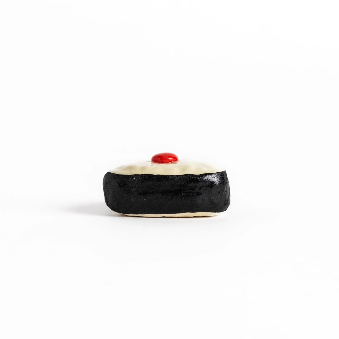 Pickled plum onigiri chopstick rest with red plum and black seaweed detail adding playful Japanese touch.