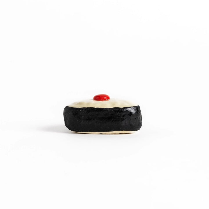 Pickled plum onigiri chopstick rest with red plum and black seaweed detail adding playful Japanese touch.
