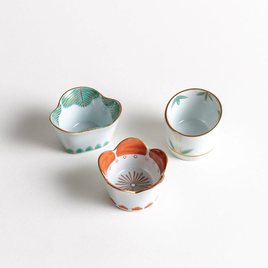 Set of three small bowls with floral motifs bamboo plum and pine each accented with elegant gold trim.