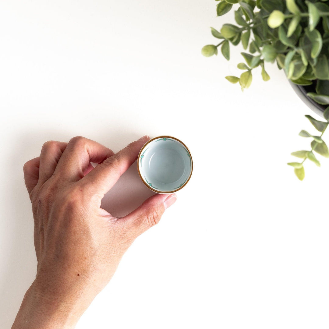 A small white bowl with a green bamboo leaf design and gold rim.