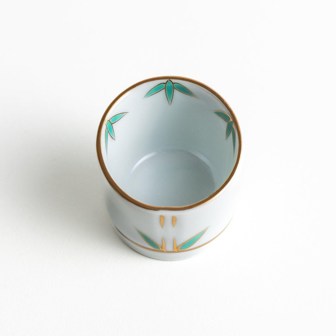 A small white bowl with a green bamboo leaf design and gold rim.