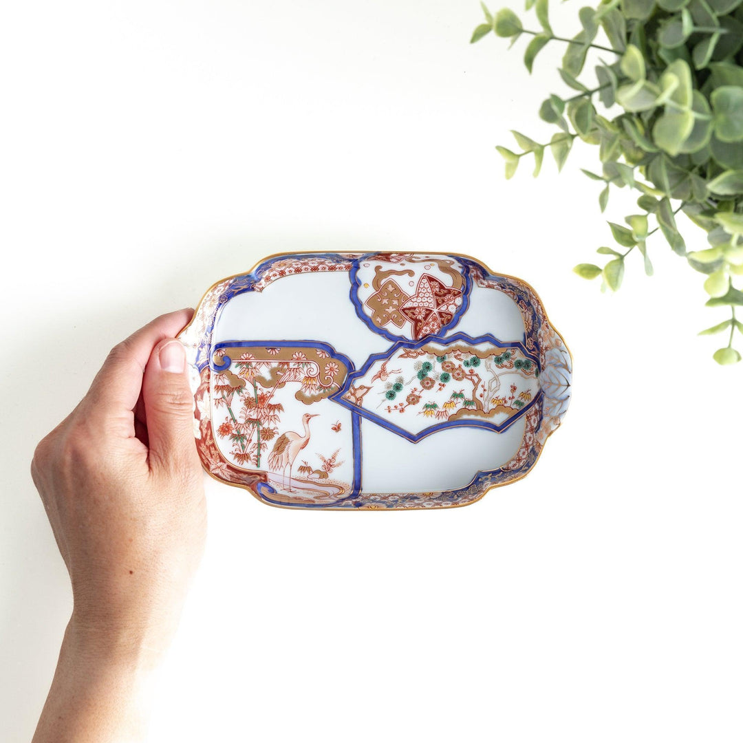 Rectangular salad plate with handles featuring cranes and trees bordered by red blue and gold patterns.