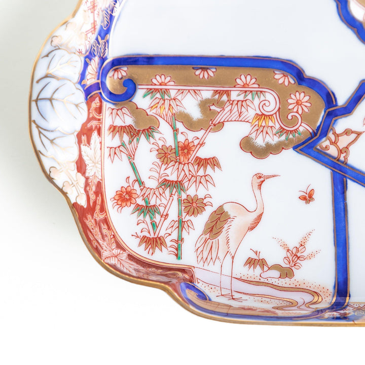 Rectangular salad plate with handles featuring cranes and trees bordered by red blue and gold patterns.