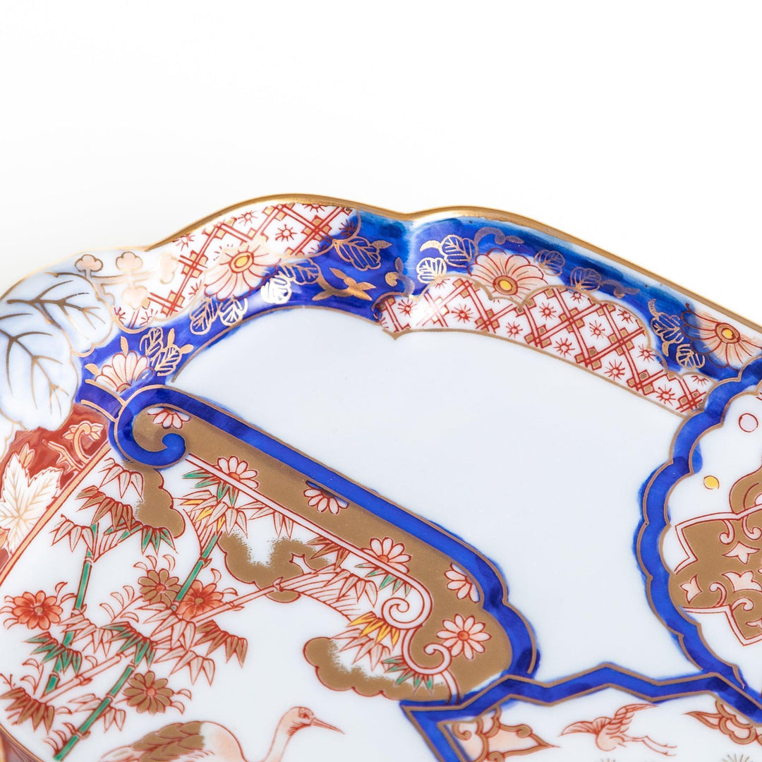 Rectangular salad plate with handles featuring cranes and trees bordered by red blue and gold patterns.