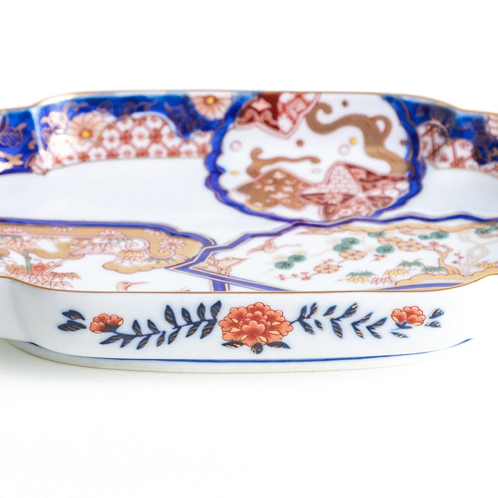 Rectangular salad plate with handles featuring cranes and trees bordered by red blue and gold patterns.