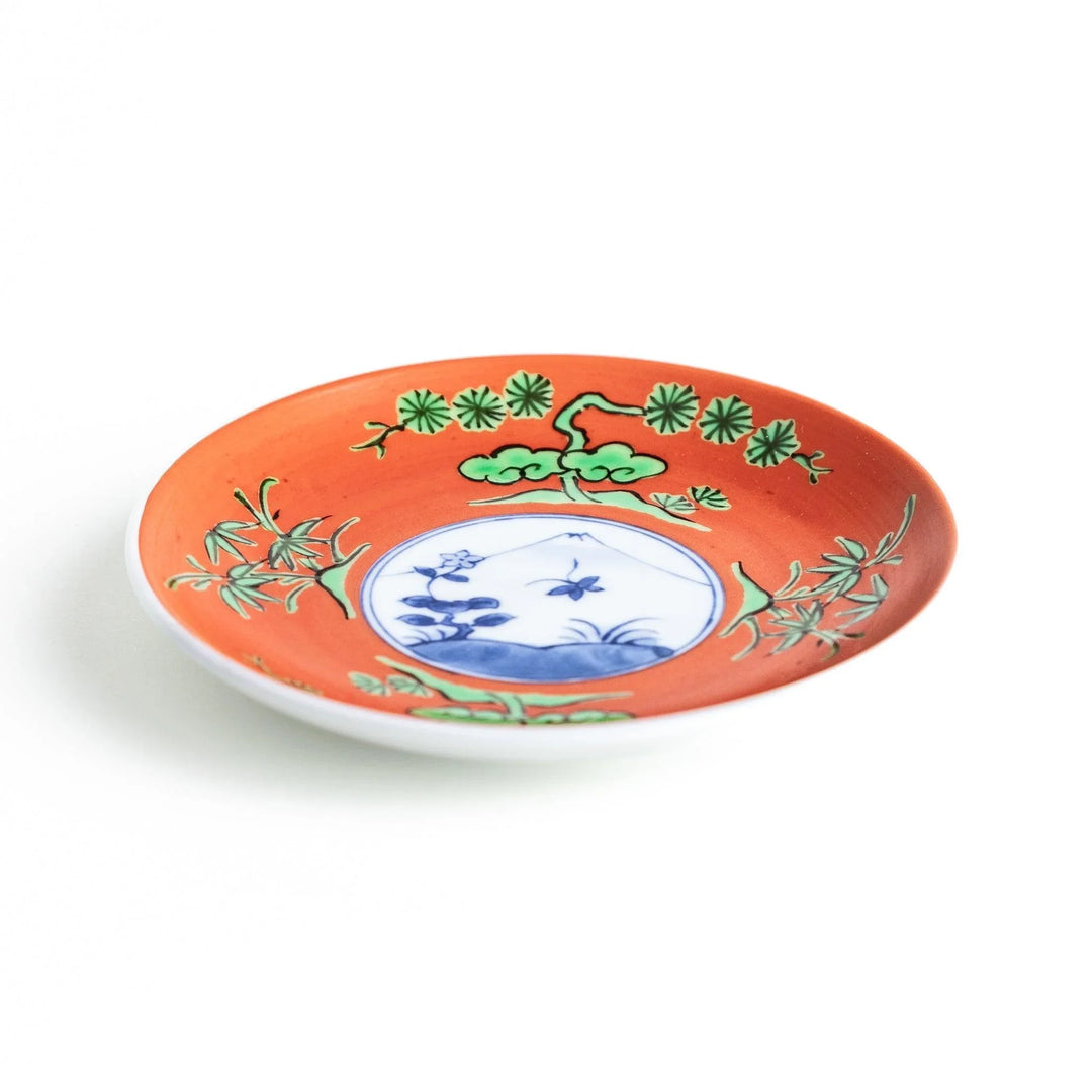 Round plate with an orange background, green leaves, and a Mount Fuji scene.