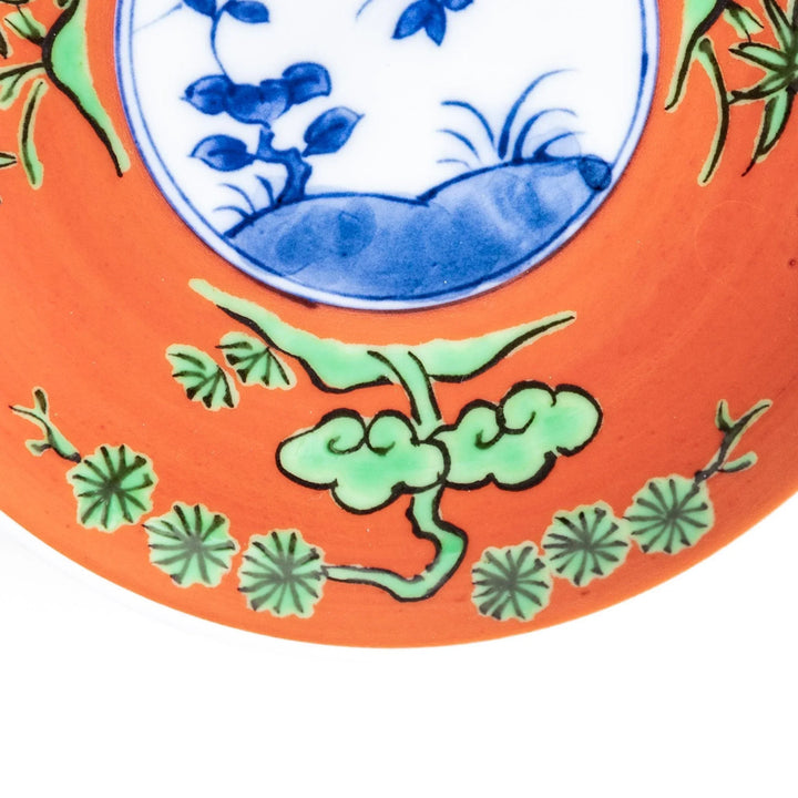 Round plate with an orange background, green leaves, and a Mount Fuji scene.