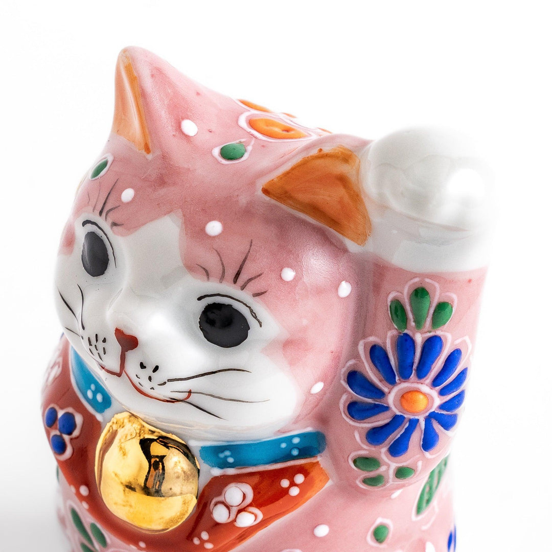 Pink blossom Maneki Neko figurine with floral patterns and gold bell symbolizing good luck and prosperity.