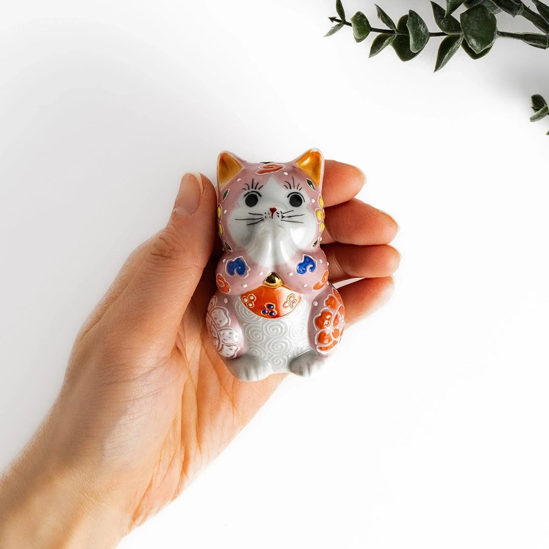 Maneki Neko figurine featuring a pink blossom design with vibrant colors and a praying posture for good fortune.