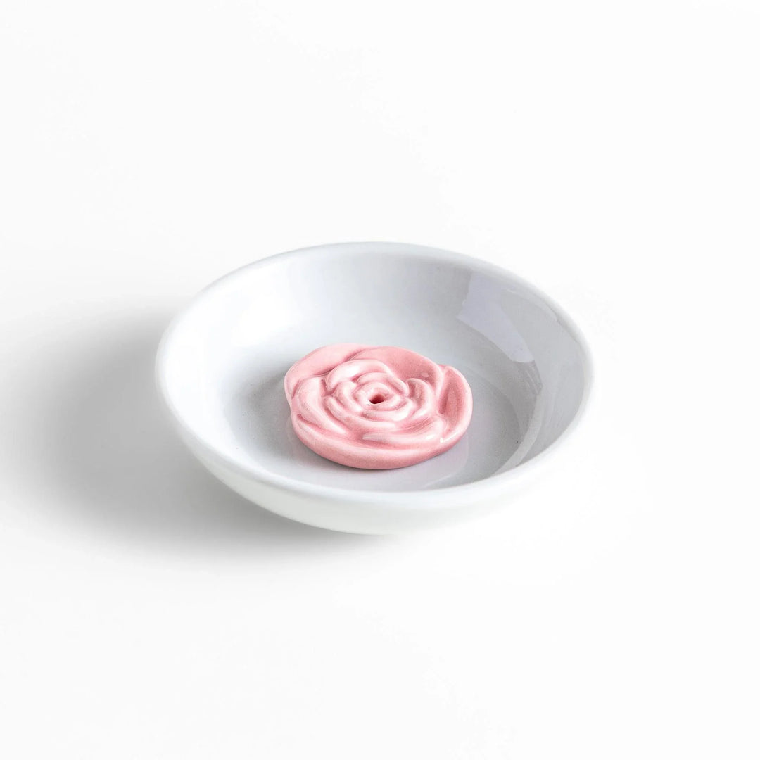 White ceramic Japanese incense holder with pink rose design adding elegant floral touch to any space.