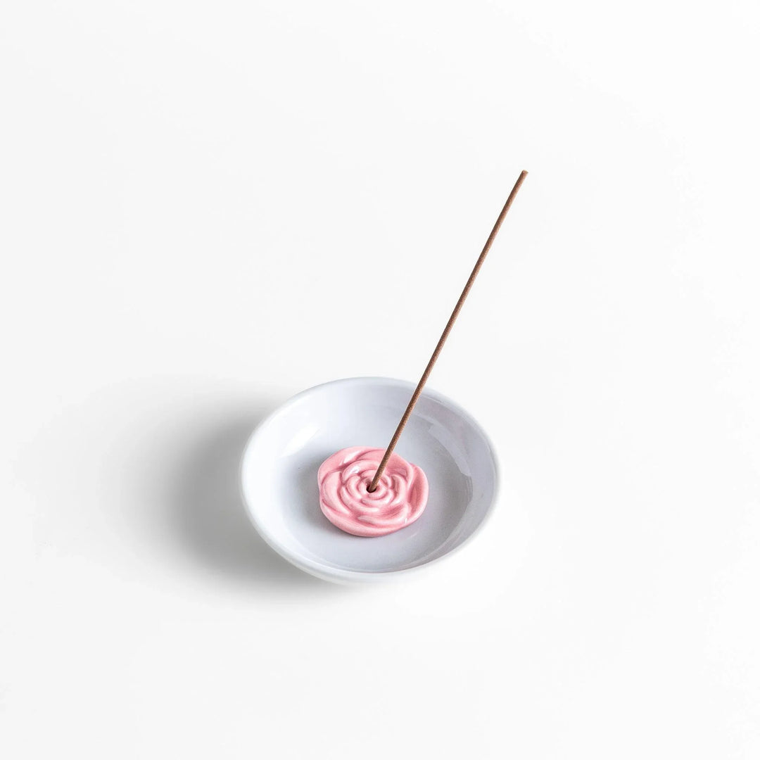White ceramic Japanese incense holder with pink rose design adding elegant floral touch to any space.