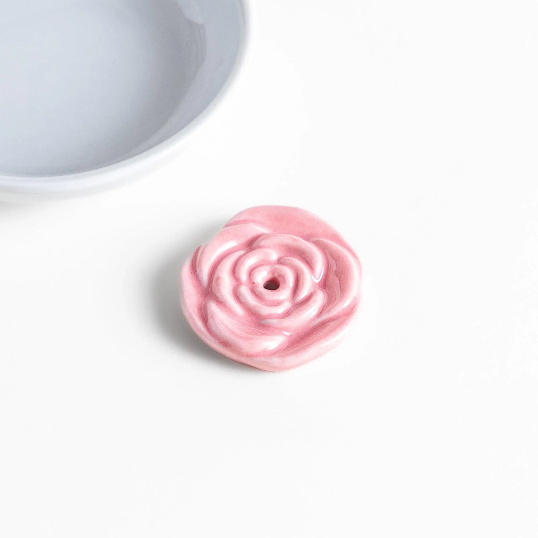 White ceramic Japanese incense holder with pink rose design adding elegant floral touch to any space.