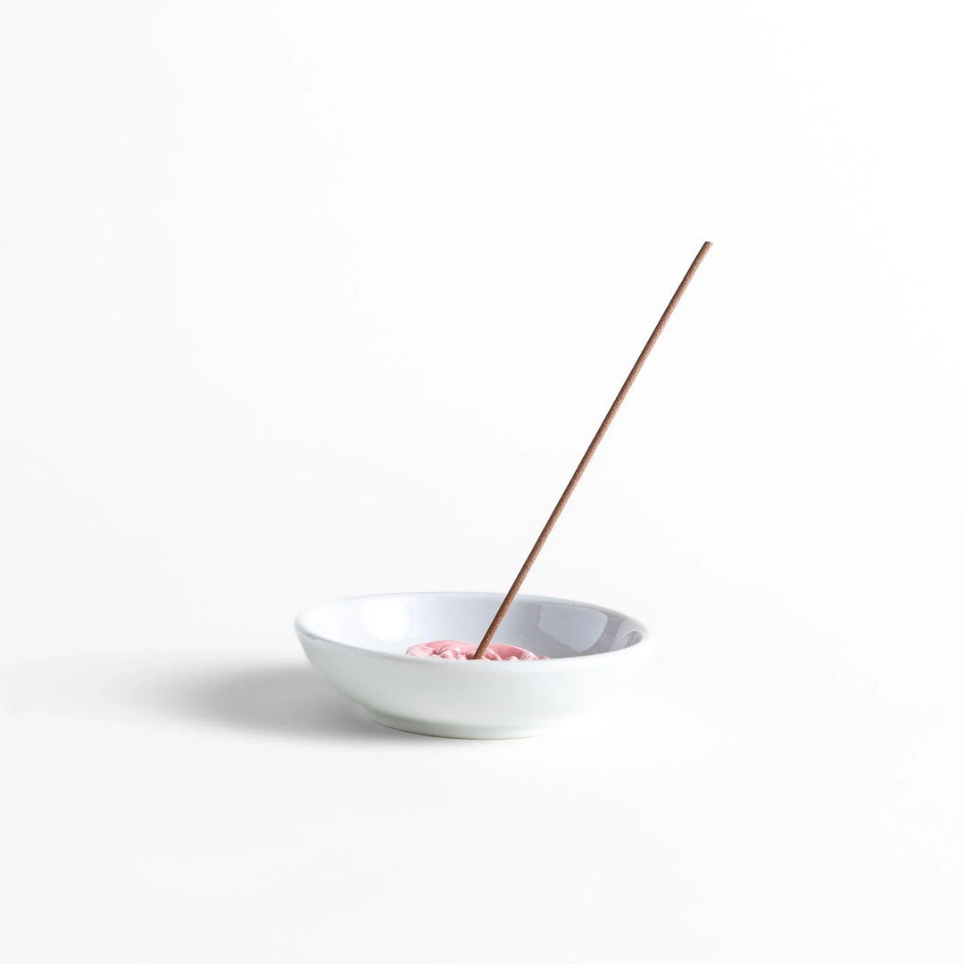 White ceramic Japanese incense holder with pink rose design adding elegant floral touch to any space.