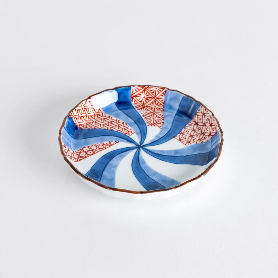 A round plate featuring a bold swirl pattern in red and blue with intricate geometric designs.