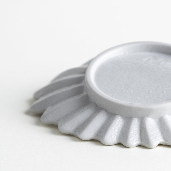 A white, leaf-shaped ceramic plate with delicate pink and gold floral decorations.