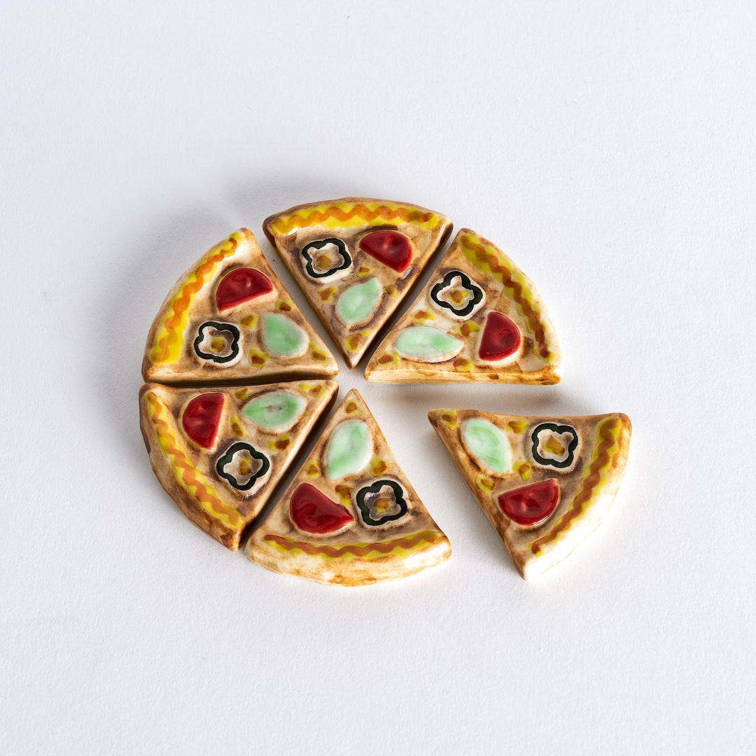 Pizza slice shaped chopstick rests arranged in circle forming full pizza adding fun touch to table setting.