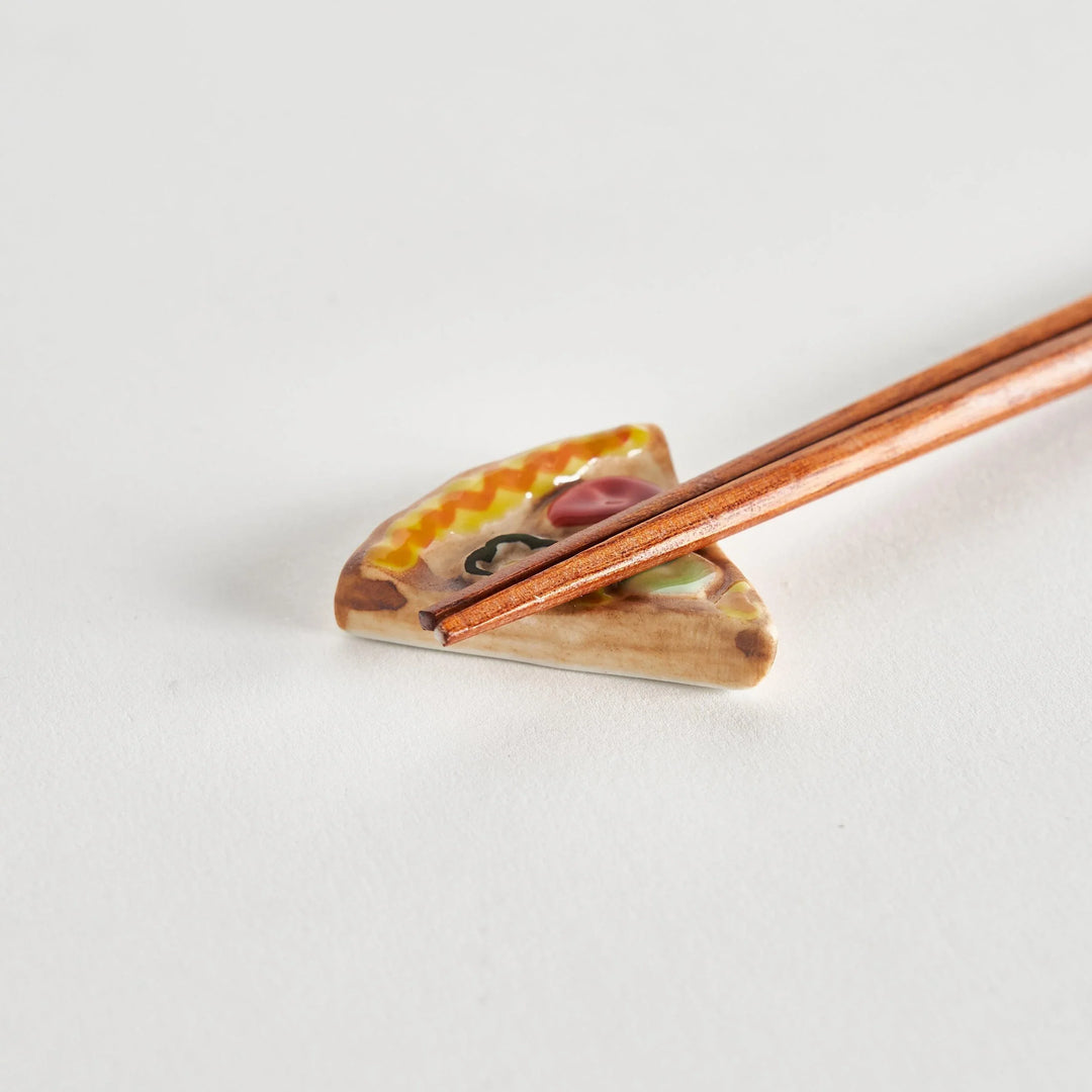 Close-up of chopstick resting on a pizza chopstick rest, showcasing the detailed pizza design.