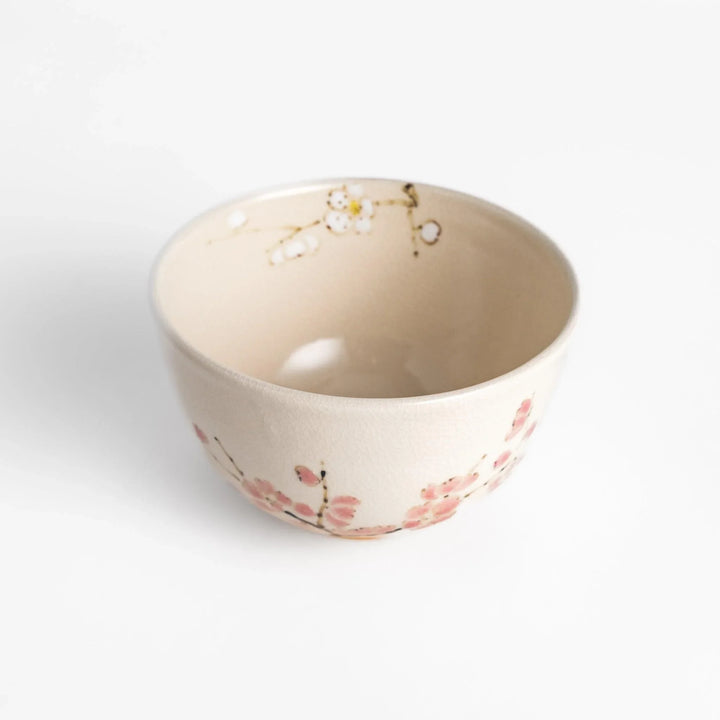 Plum Blossom Matcha Bowl with pink floral designs on a cream surface, adding elegance to your matcha moments.