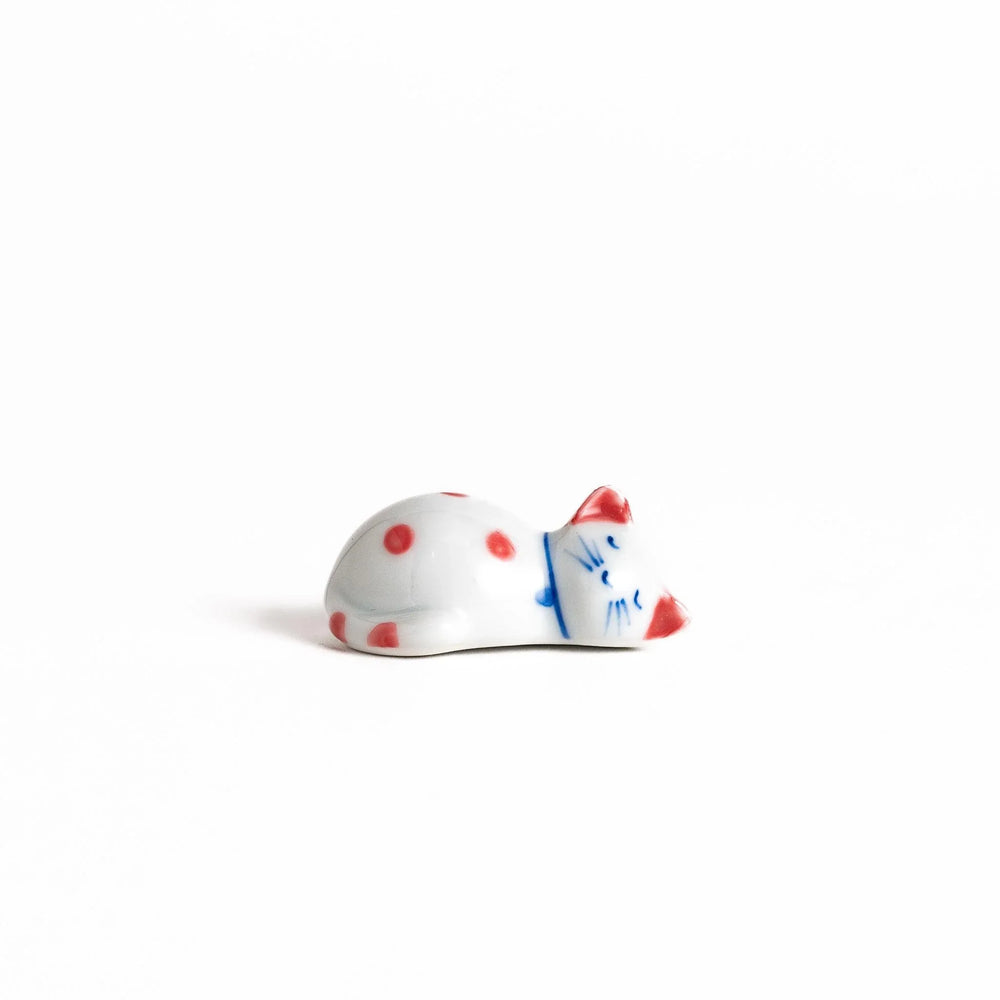 Adorable white ceramic chopstick rest shaped like a sleeping cat with red dots, adding a playful touch to your table setting.