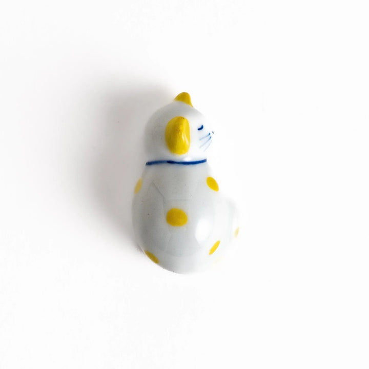 White ceramic cat chopstick rest with yellow dots in sleeping pose adding cheerful touch to dining.