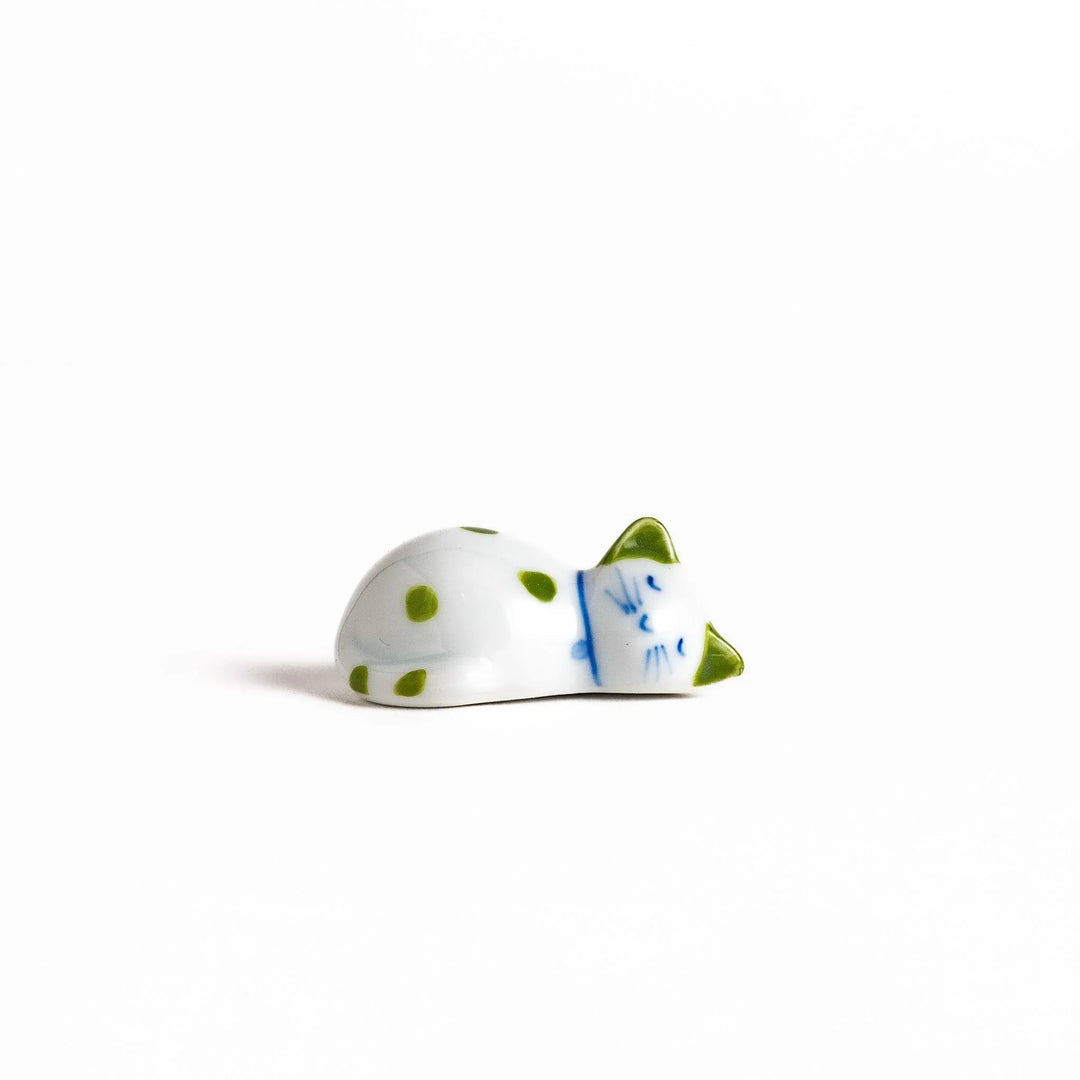 White ceramic cat chopstick rest with green dots in sleeping pose bringing natural charm to table.